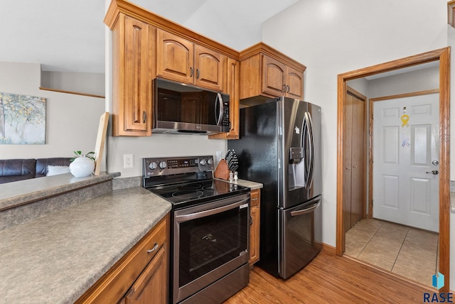 kitchen with brown cabinetry, light wood-type flooring, and stainless steel appliances