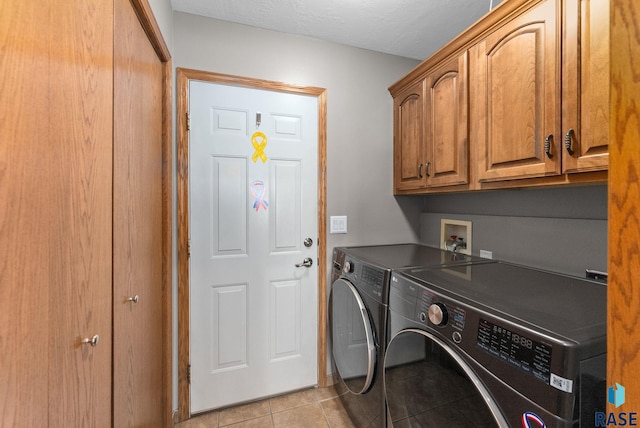 laundry room with cabinet space, a textured ceiling, washing machine and dryer, and light tile patterned flooring