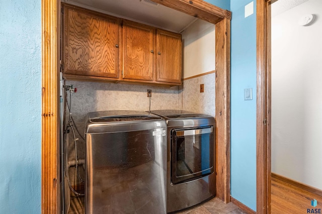 washroom with baseboards, cabinet space, separate washer and dryer, and visible vents