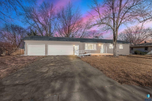 ranch-style house with a porch, an attached garage, and driveway