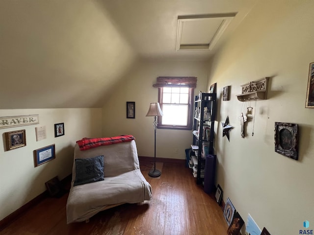 living area featuring attic access, wood finished floors, baseboards, and vaulted ceiling