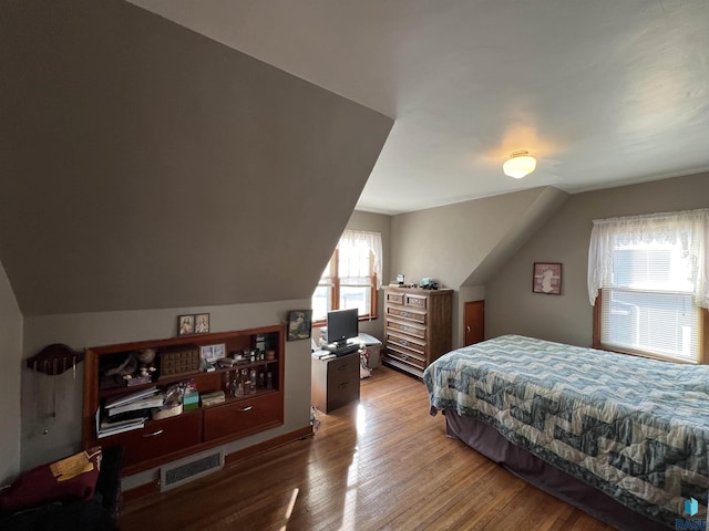 bedroom with vaulted ceiling, wood finished floors, and visible vents