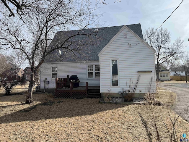 rear view of property featuring a wooden deck and roof with shingles