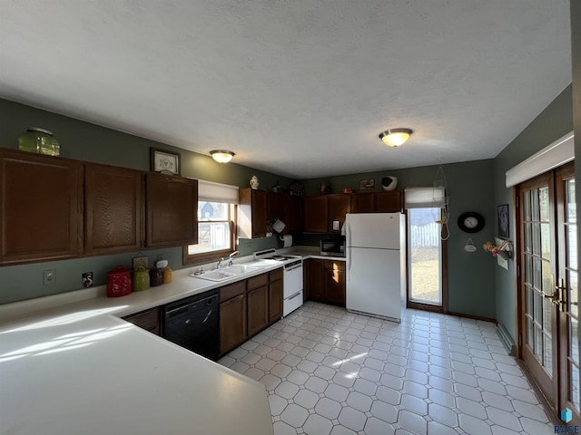 kitchen featuring light floors, light countertops, french doors, white appliances, and a sink