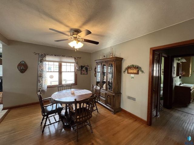 dining room featuring ceiling fan, wood finished floors, visible vents, and baseboards