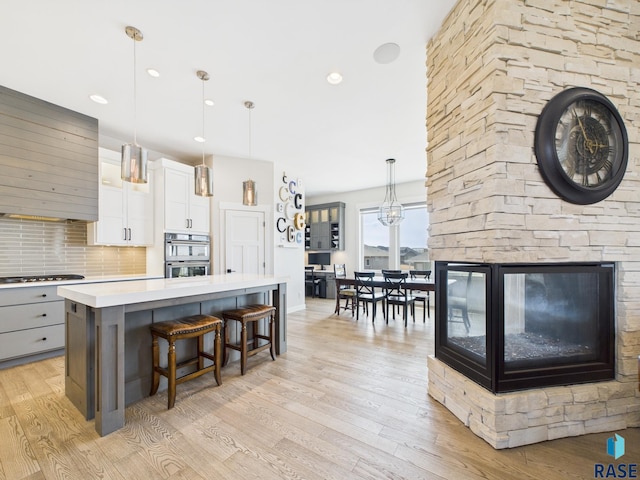 kitchen with a kitchen island, light countertops, light wood-style floors, a kitchen breakfast bar, and backsplash