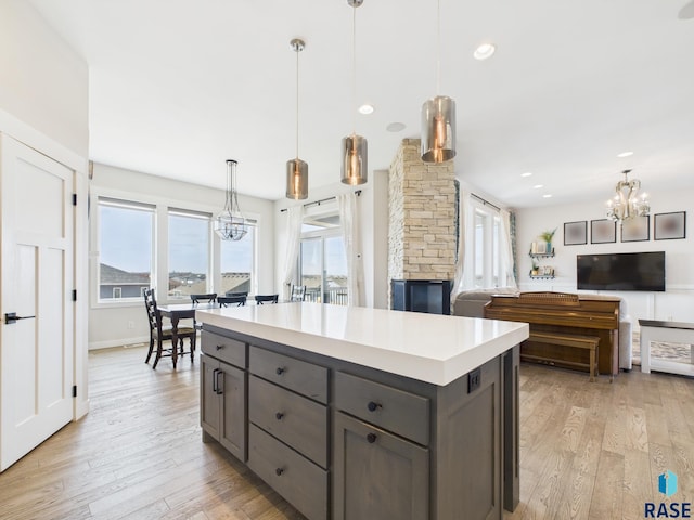 kitchen with gray cabinets, light countertops, light wood-style floors, decorative light fixtures, and a center island