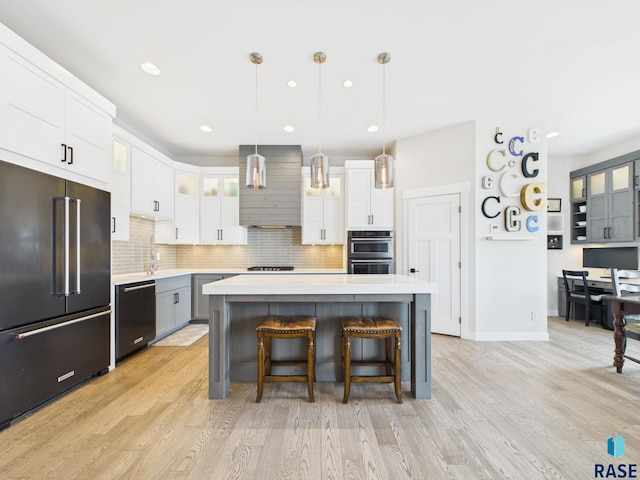 kitchen featuring wall chimney range hood, light countertops, black dishwasher, high end fridge, and white cabinetry