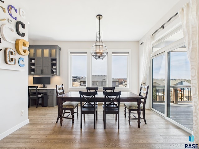 dining area featuring a chandelier, plenty of natural light, light wood-type flooring, and baseboards