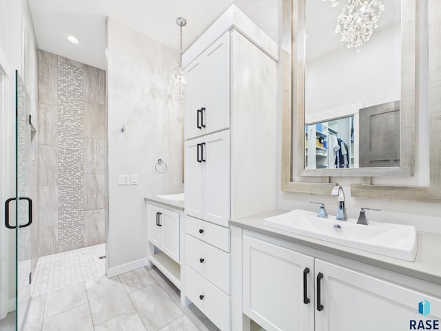 bathroom featuring baseboards, vanity, an inviting chandelier, and a shower stall