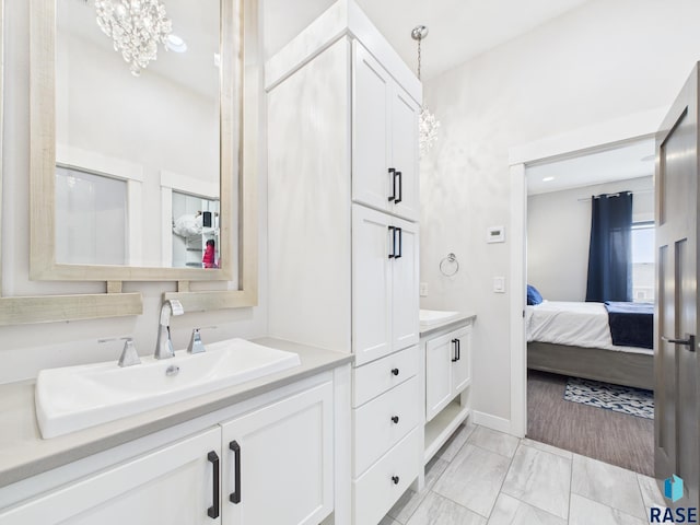 ensuite bathroom with double vanity, ensuite bathroom, an inviting chandelier, and a sink