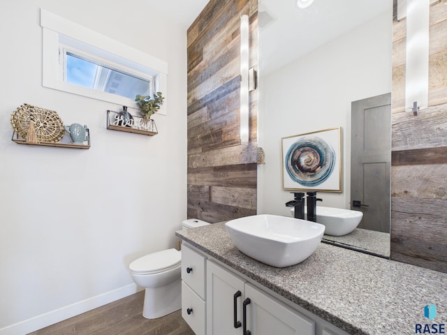 bathroom featuring toilet, vanity, baseboards, and wood finished floors