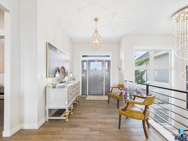 entryway featuring a chandelier, baseboards, and wood finished floors