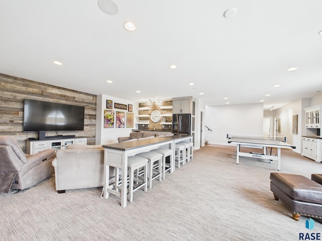 living area with light carpet, recessed lighting, wood walls, baseboards, and an accent wall