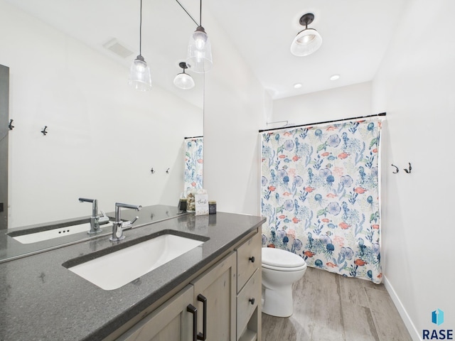 full bath with visible vents, a shower with curtain, toilet, wood finished floors, and vanity