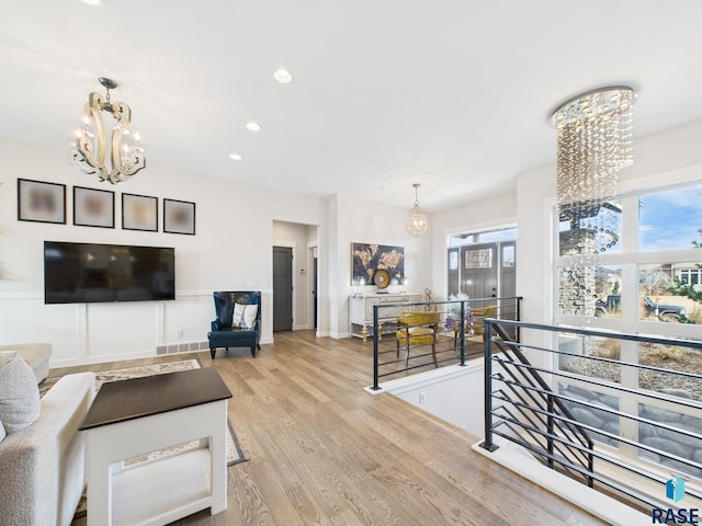 living area featuring baseboards, visible vents, recessed lighting, light wood-type flooring, and a chandelier