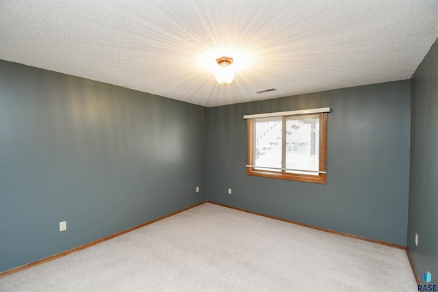 unfurnished room with light carpet, visible vents, a textured ceiling, and baseboards