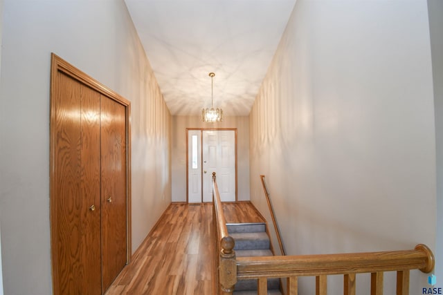 doorway to outside featuring a chandelier, light wood-style flooring, and stairs