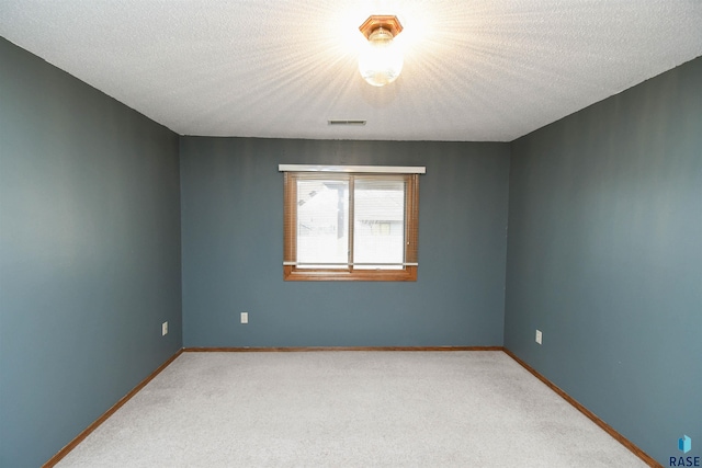 empty room with a textured ceiling, baseboards, and carpet floors