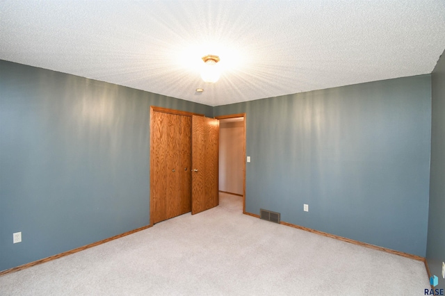 empty room featuring visible vents, a textured ceiling, baseboards, and carpet floors