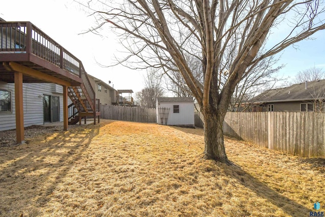 view of yard with a fenced backyard, a shed, an outdoor structure, a wooden deck, and stairs