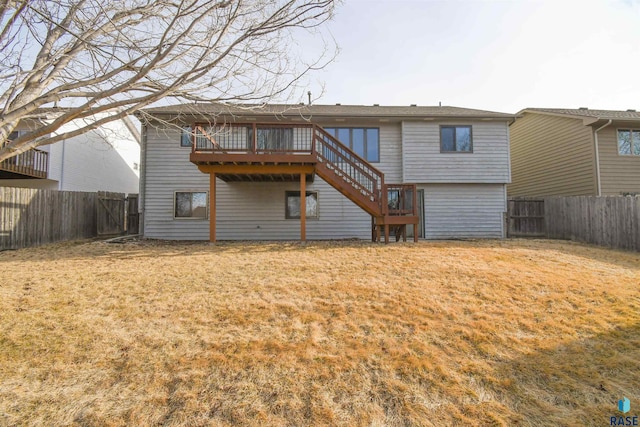 back of property featuring stairway, a deck, a lawn, and a fenced backyard