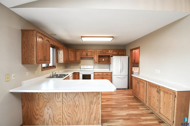 kitchen featuring white appliances, a peninsula, light wood-style flooring, a sink, and light countertops