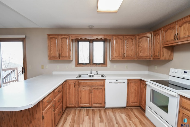 kitchen featuring white appliances, a peninsula, a sink, brown cabinets, and a wealth of natural light