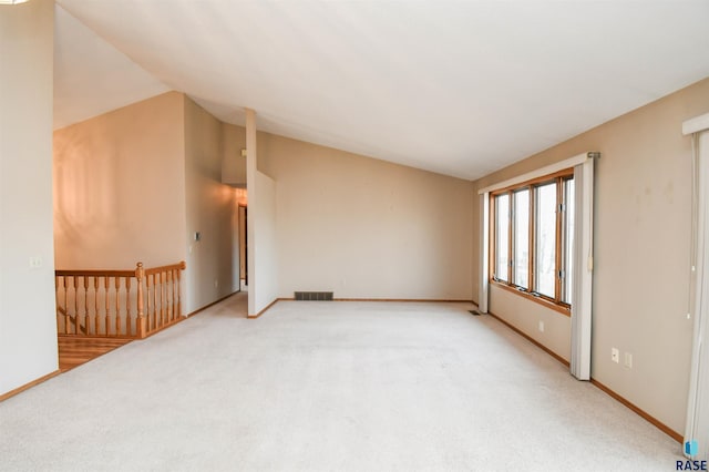 unfurnished room with baseboards, visible vents, lofted ceiling, and light carpet