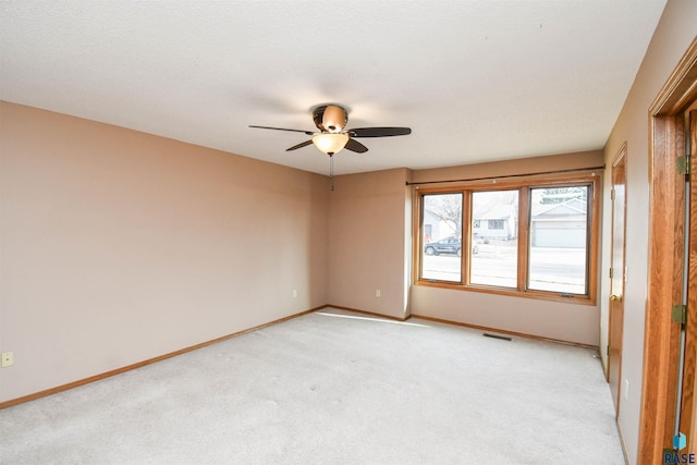 empty room with a ceiling fan, baseboards, visible vents, and light carpet