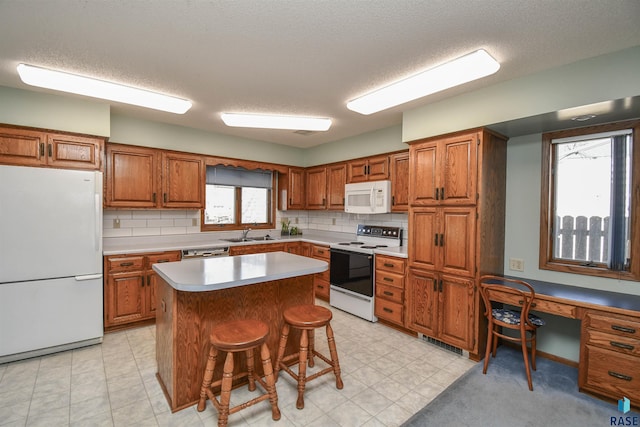 kitchen featuring white appliances, light countertops, brown cabinets, and a kitchen island