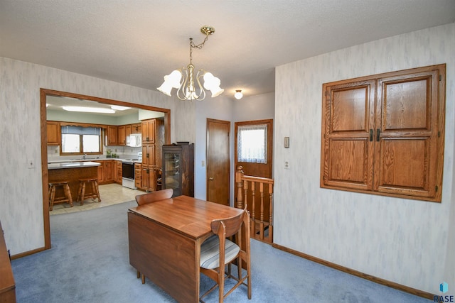 dining room featuring baseboards, a chandelier, and light carpet