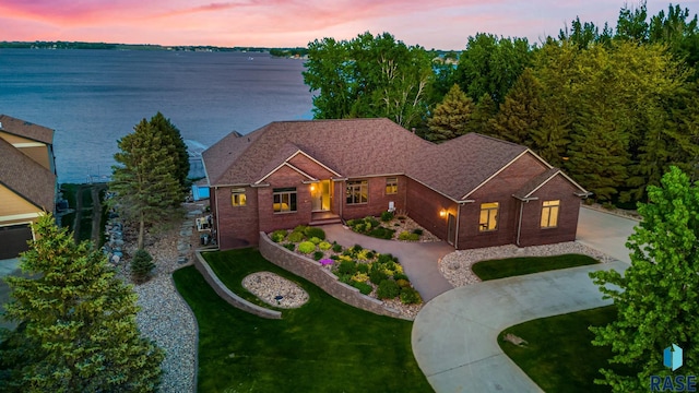 view of front of house featuring a water view, brick siding, and driveway