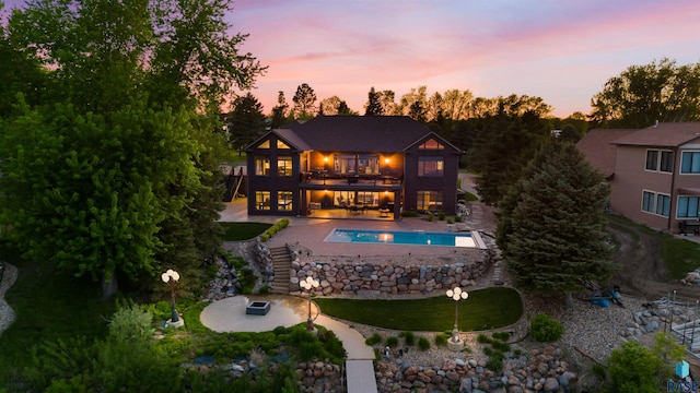 back of house with a balcony, an outdoor pool, and a patio