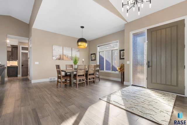 dining area featuring visible vents, wood finished floors, baseboards, and vaulted ceiling