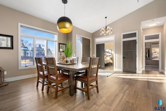 dining area featuring baseboards, lofted ceiling, an inviting chandelier, and light wood finished floors