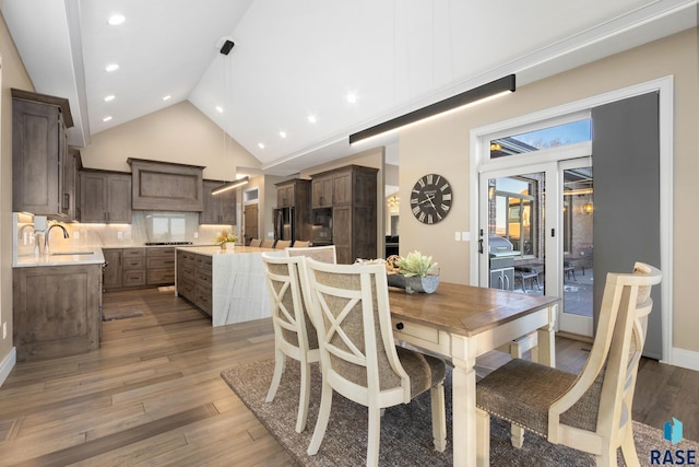 dining area featuring recessed lighting, high vaulted ceiling, baseboards, and wood finished floors