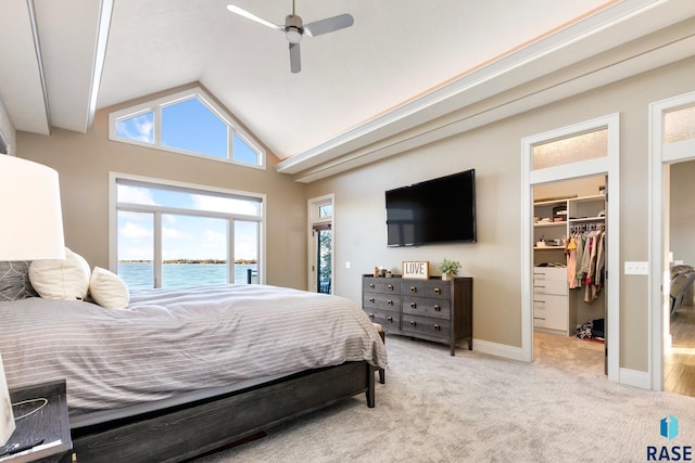 bedroom featuring baseboards, ceiling fan, vaulted ceiling, a spacious closet, and light carpet