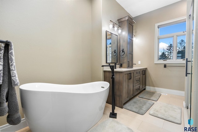 full bathroom with tile patterned floors, a soaking tub, vanity, and baseboards