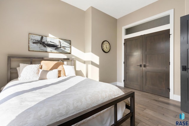 bedroom with a closet, baseboards, and light wood finished floors