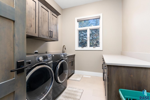 washroom featuring washing machine and clothes dryer, baseboards, light floors, cabinet space, and a sink