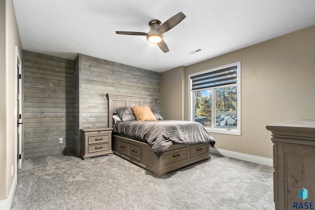 bedroom featuring visible vents, light carpet, wooden walls, baseboards, and ceiling fan