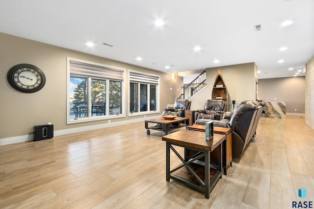 living area featuring recessed lighting, stairs, light wood-type flooring, and baseboards