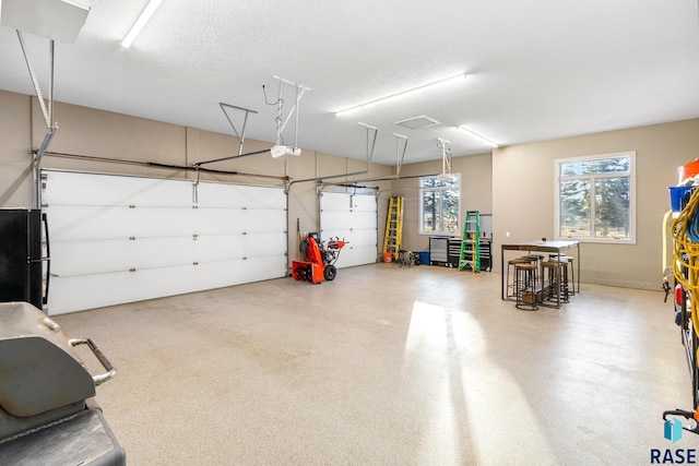 garage with a garage door opener and freestanding refrigerator