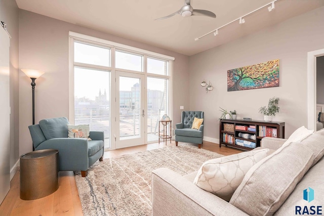 living room with baseboards, a city view, wood finished floors, and a ceiling fan