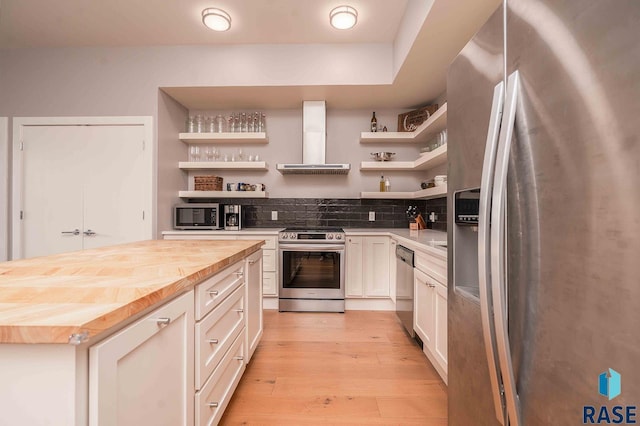 kitchen with open shelves, wall chimney range hood, wooden counters, and stainless steel appliances