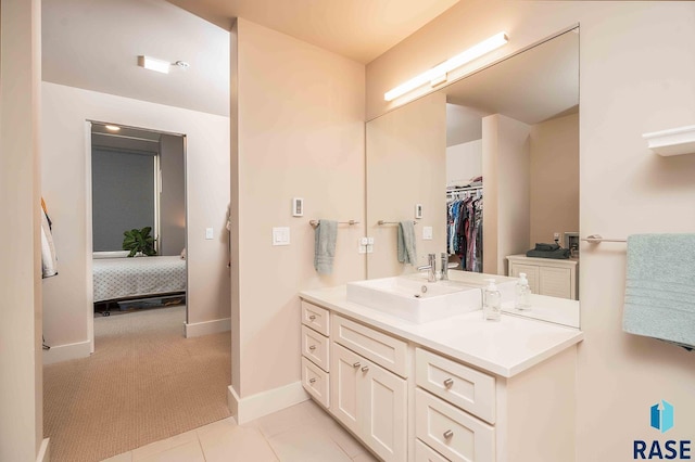 full bathroom with tile patterned flooring, a walk in closet, baseboards, ensuite bathroom, and vanity