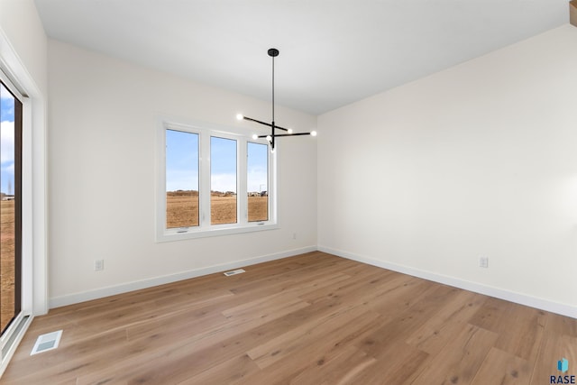 unfurnished room featuring visible vents, light wood-type flooring, and baseboards