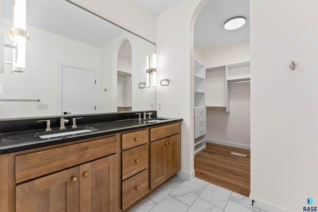 full bathroom featuring a sink, baseboards, marble finish floor, and double vanity