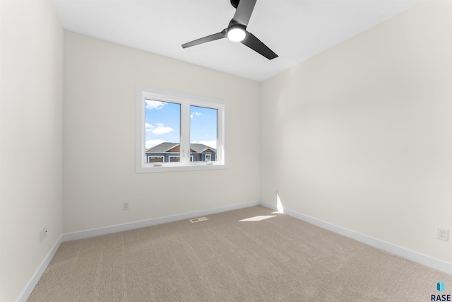 empty room with a ceiling fan, light colored carpet, visible vents, and baseboards